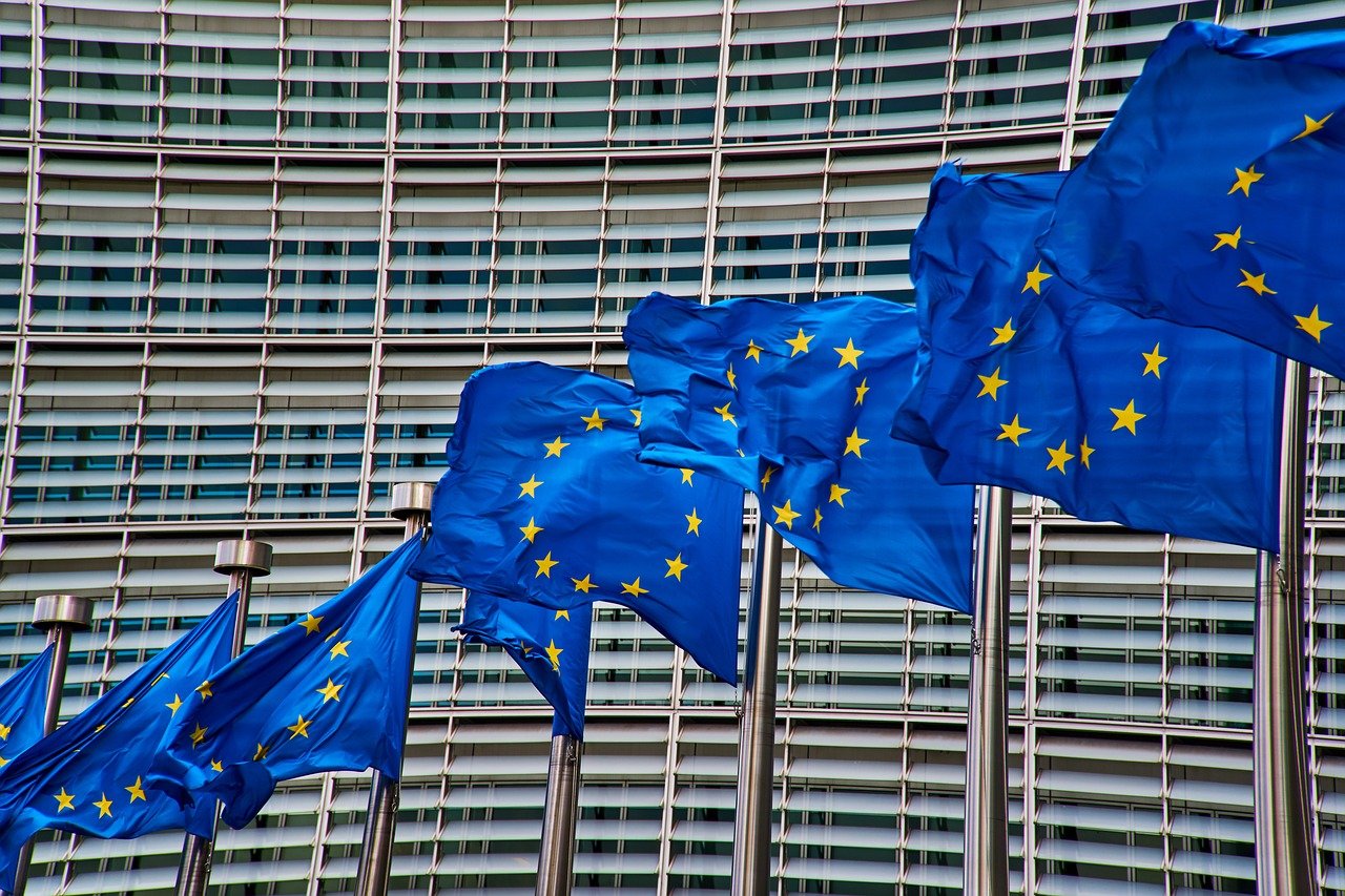 Een rij EU vlaggen op vlaggenstokken voor een kantoorgebouw